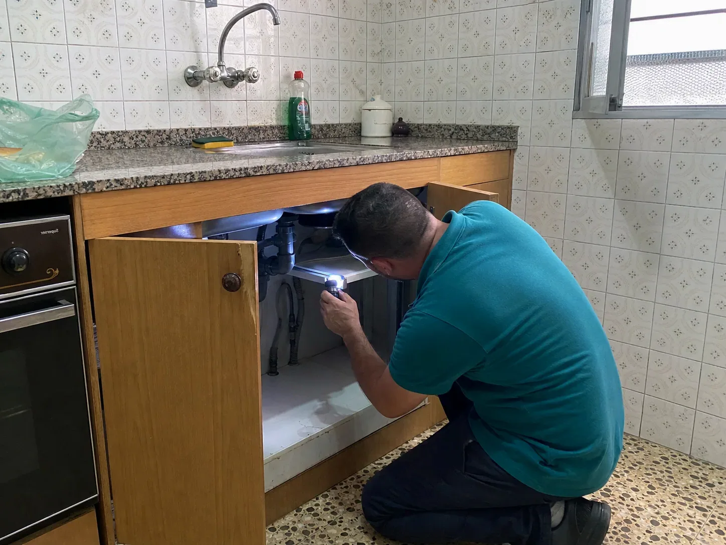 Técnico de CaldesControl inspeccionando una cocina con linterna